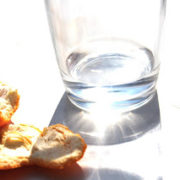 Image d'un verre inondé de lumière posé à côté d'écorces de mandarine