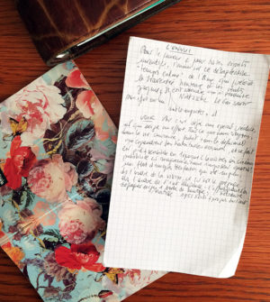 Photo en gros plan d'une lettre posée en partie sur un cahier à fleur, à plat sur un bureau deviné