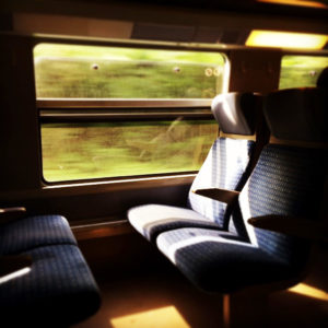 Photo de l'intérieur d'un TGV, la lumière éclairant deux places assises à travers la vitre