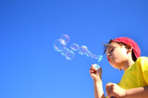 Photo d'un enfant faisant des bulles sur un fond ciel azur
