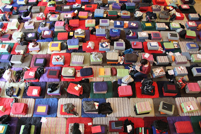Photo en plongée du tapis de coussins de méditation couvrant la salle Wagram pendant un évènement de l'École occidentale de méditation, fondée par Fabrice Midal