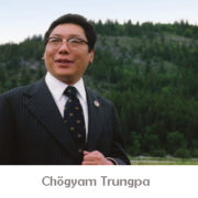 Photo de Chogyam Trungpa en costume sombre devant une colline verte et boisée