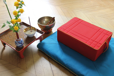 Photo d'un coussin de méditation rouge posé sur un tapis de méditation turquoise