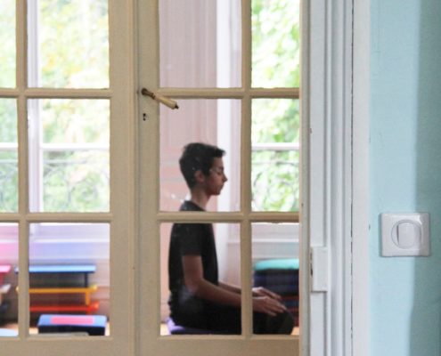 Photo de Pablo, de profil, pratiquant la méditation derrière une porte vitrée