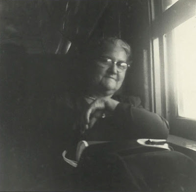 Phot noir et blanc d'une femme âgée, assise de face près d'une fenêtre