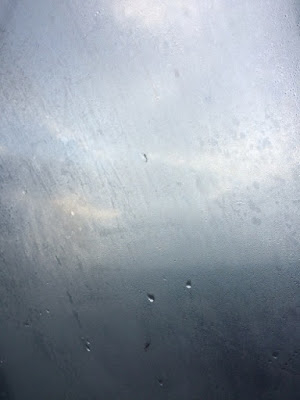 Photo d'un ciel de mauvais temps vu à travers une vitre sur laquelle coulent quelques gouttes de pluie