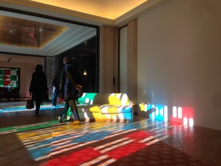 Photo d'une pièce, dans la pénombre, une partie du sol éclairé par la lumière extérieure formant une mosaïque de couleurs