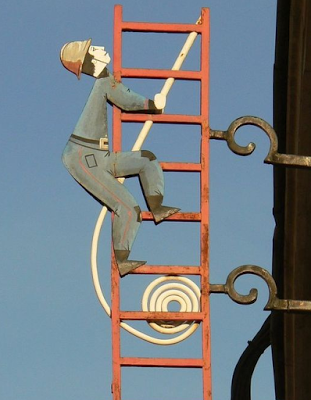 Photo d'une oeuvre de ferraillerie représentant un pompier sur une grand échelle