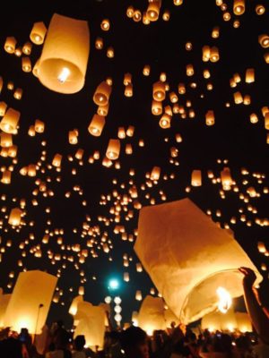 Photographie montrant des lanternes volantes s'élevant dans le ciel de nuit.