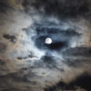 Photographie d'un ciel nuageux, une nuit de pleine Lune.