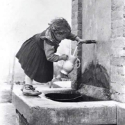 Enfant remplissant un pichet à eau à une fontaine, noir et blanc